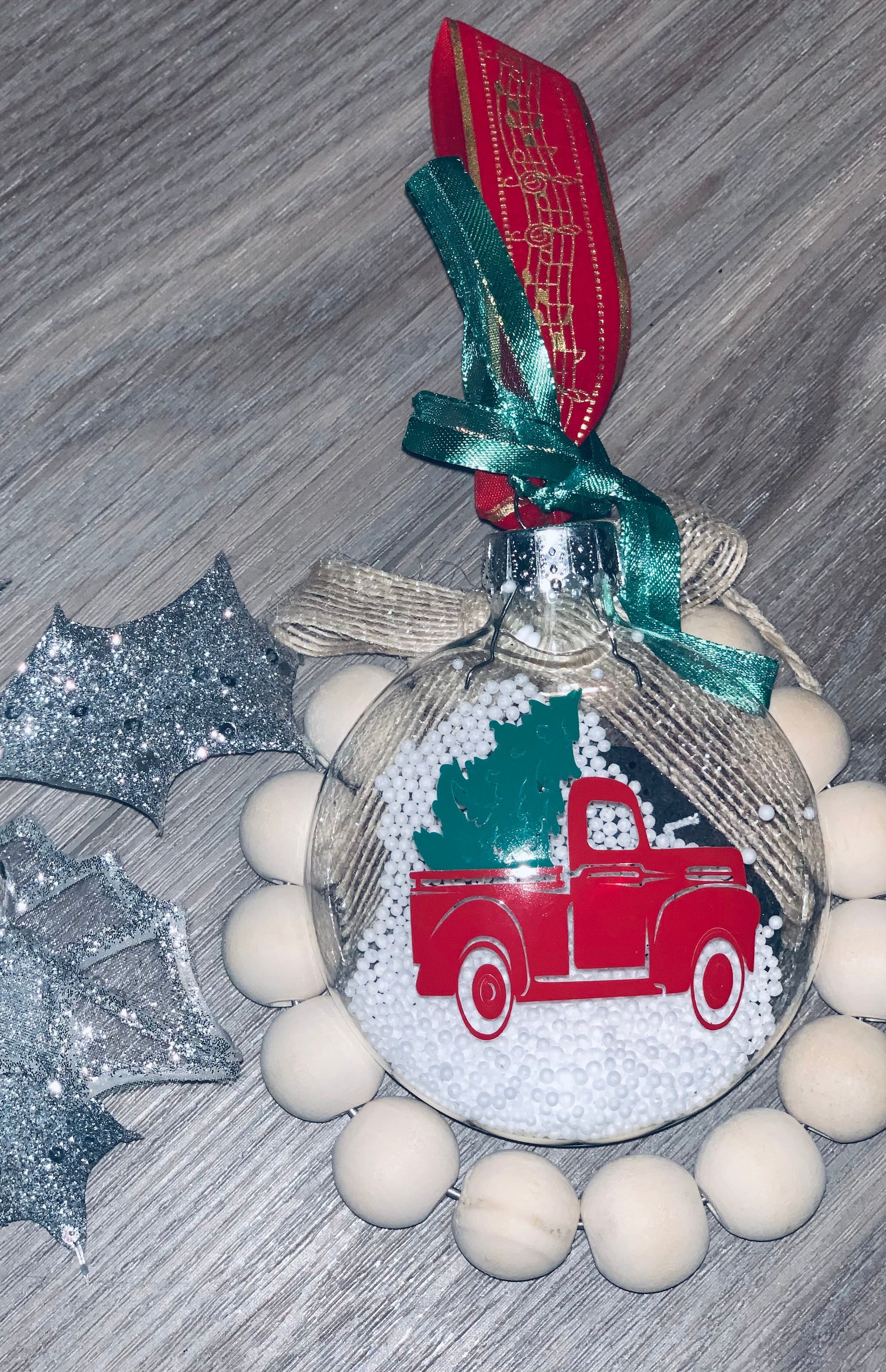 Flat glass ornament with red Christmas truck and tree.